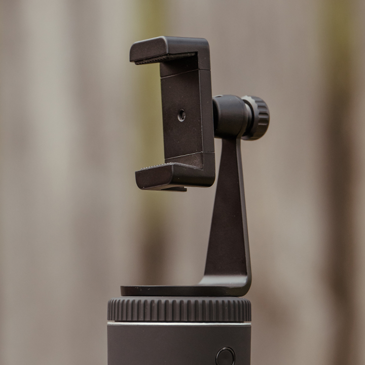 Adjustable smartphone mount on tripod for equestrian filming.