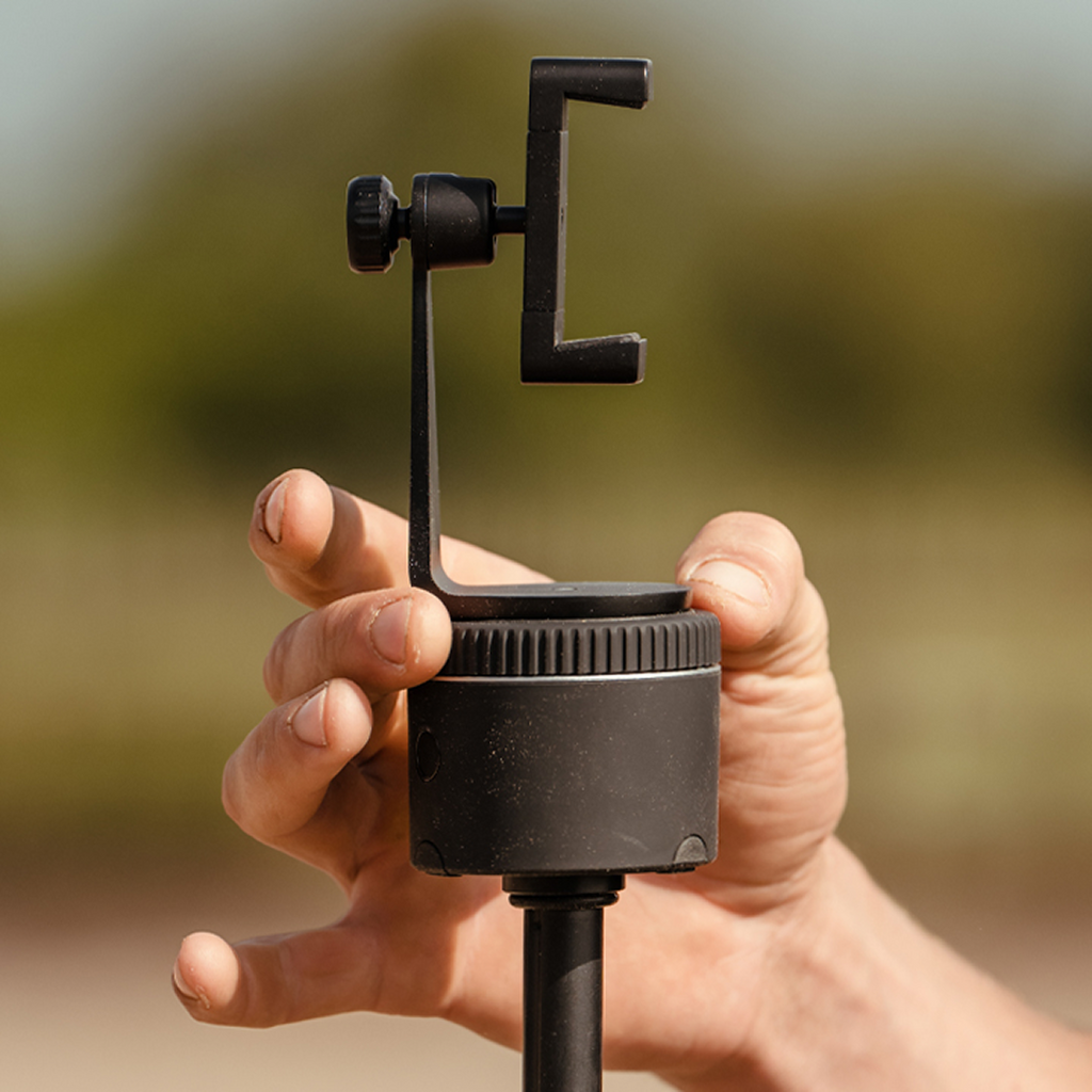 Adjustable smartphone mount in hand, compatible with Pivo Pods and tripods.