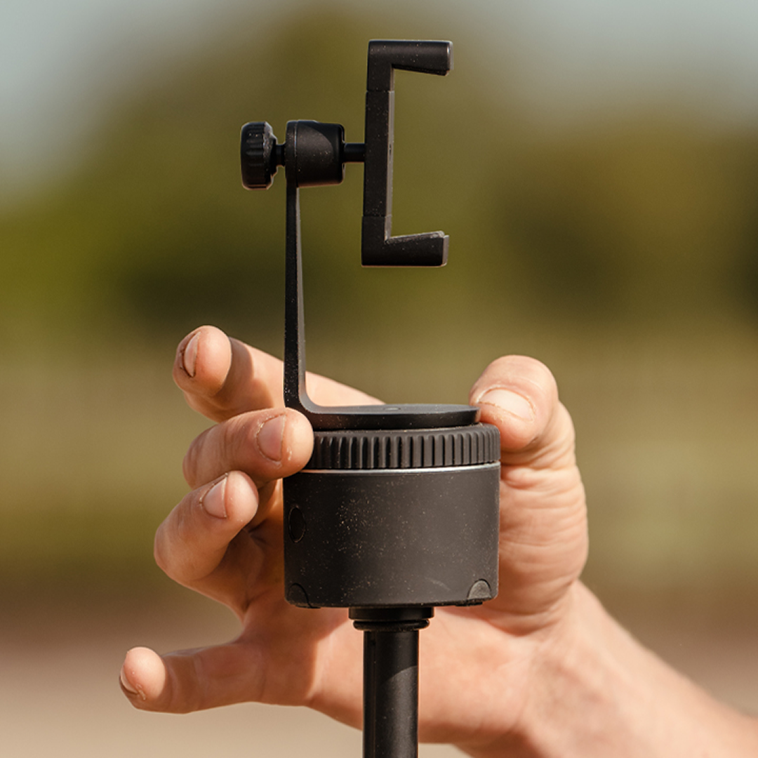Adjustable smartphone mount in hand, compatible with Pivo Pods and tripods.